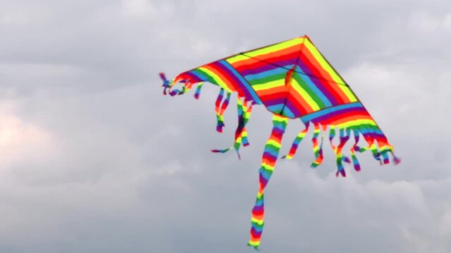 Colorful bright kite flying in the wind. Close up with kite against cloudy sky