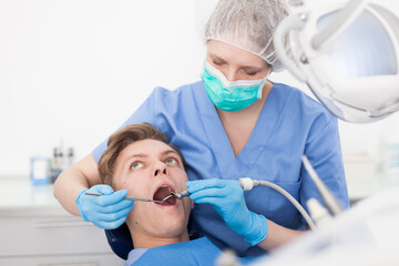 Male patient sitting on chair in dental office getting dentist treatment. High quality photo