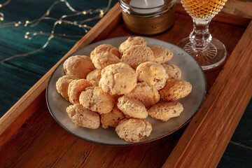 Amaretti, traditional Italian almond cookies, with a glass of Amaretto liqueur, a close-up on a dark blue wooden background