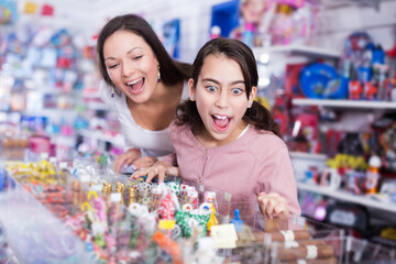 Fototapeta na wymiar portrait of mother with happy daughter delighted with choosing lollipop in store