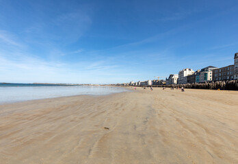  Romantic walk of people before sunset on the picturesque beach of Saint Malo. Brittany, France