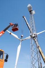Construction of a wind power plant. Installers use a truck crane and aerial platform to raise the wind turbine rotor. Photo taken on a sunny summer day in Russia