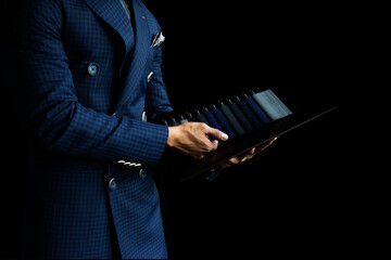 The dressmaker is choosing the fabric to cut the suit. Customers are choosing the color of the fabric in order to tailor the suit.