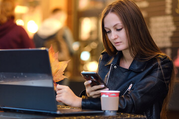 Beautiful Attractive Asian woman working with laptop smile and talking with customer in smartphone to get idea and requirement for success job outside office in coffee shop,Business Concept,Warm Tone