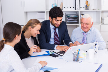 Office workers are working together at computer in the office.