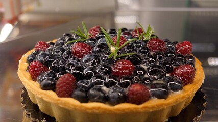 Confectionery shop. Close up of freshly baked berry tart with cream filling. Desserts and sweets concept. 