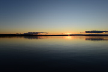 Fototapeta na wymiar Sunset on the horizon over a calm water surface lake