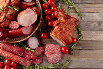 Food tray with delicious salami, ham, fresh sausages, tomato, and rosemary.