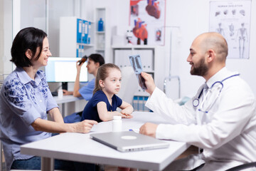 Pediatrician examining sick child x-ray during medical consultation in hospital office. Healthcare physician specialist in medicine providing health care services treatment examination.