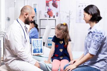 Pediatrician explaining radiography for sick child and mother in hospital office. Healthcare physician specialist in medicine providing health care services treatment examination.