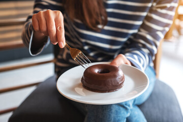 Closeup image of a woman holding and eating chocolate donut