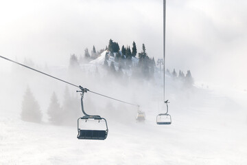 Ski lift on the background of mountains in the fog. Beautiful luxury best winter holiday background.