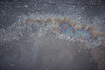 Gas stain on wet asphalt caused by a leak under a car or truck