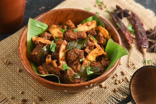 Beef curry Kerala style meat beef or mutton curry garnished with fried coconut slices and curry leaves south Indian style. Bowl of tasty mutton roast with Indian spices