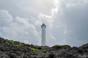 Cape Zanpa Lighthouse, Okinawa, Japan with surrounding volcanic rock formation and silver line sky with grey clouds