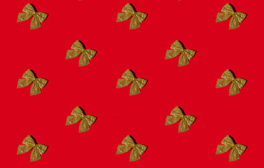 Red Xmas background. Seamless pattern. Gold glitter bow. New Year party decor. Minimalist arrangement of shimmering shiny glamour ornament isolated on bright surface.