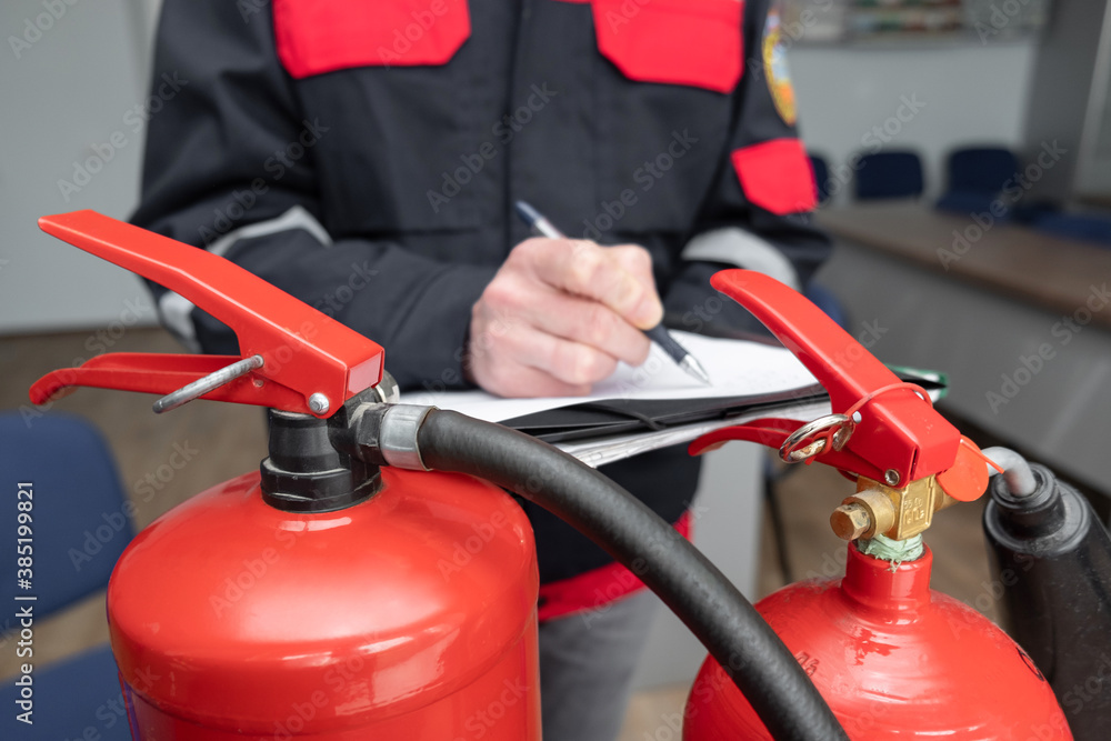 Wall mural engineer professional are checking a fire extinguisher and writes data to the check log. fire alarm 