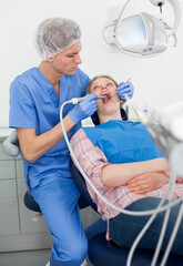 Professional dentist examining and performing treatment to young woman. High quality photo