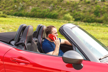young man making a phone call while driving coupe cabriolet car