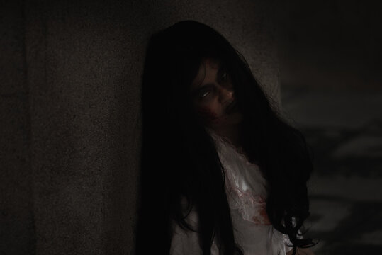 Female zombie in blood. Asian Woman ghost with blood. Horror creepy scary fear she sitting in a dark house. Hair covering the face, Halloween festival concept