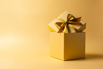 Golden gift box with shiny satin bow for surprise