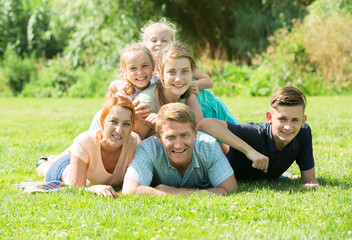 Family with four kids lying in park on summer day