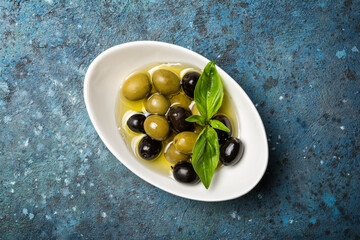 Bowl of delicious green and black olives in oil