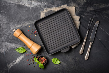 Grill pan with bright spices, basil leaves, pepper mill and silver cutlery for tasty cooking - obrazy, fototapety, plakaty