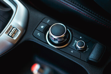 modern car media and navigation control buttons and regulator. black leather with red line interior details. close up