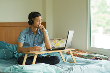 Teenage of asian boy with serious face looking to laptop and wearing headshot, online class and e...