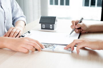 Fototapeta premium A real estate agent with rental homes and home insurance for clients to sign contracts under a formal home lease agreement. Home rental and insurance concept
