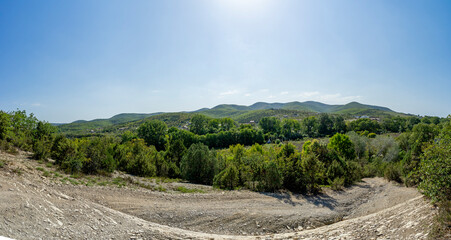 Panorama with a view of a dirt road and mountains in the background on a Sunny warm day.