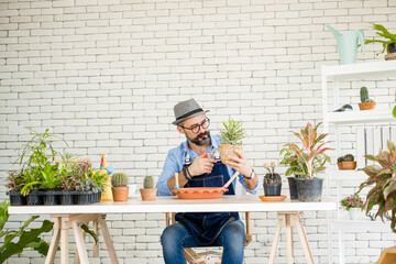 An elderly man wearing handsome glasses and a beard enjoys taking care of trees, pruning trees with...