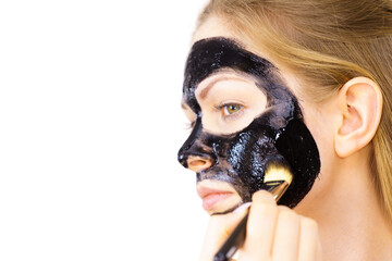 Woman applying black mud mask to face