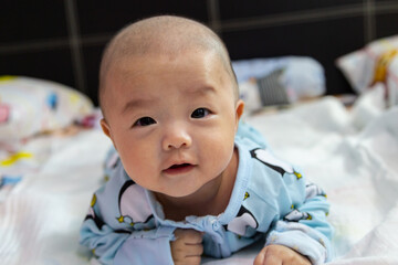 Adorable baby boy during tummy time with toy bear. Newborn child relaxing in bed