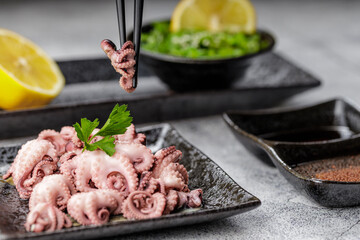 Traditional japanese or seafood concept. Delicious and healthy boiled mini octopus and wakame or seaweed salad with soy sauce and lemon served with chopstick.