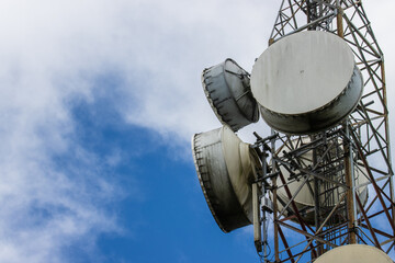 Telecommunication tower with moving clouds over blue sky