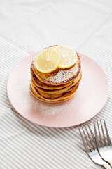 Homemade Lemon Ricotta Pancakes on a pink plate, side view.