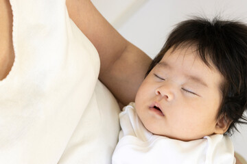 30代の母親と、抱っこされ寝ている赤ちゃん