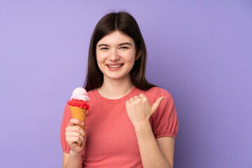 Young Ukrainian teenager girl holding a cornet ice cream over isolated purple background pointing to the side to present a product
