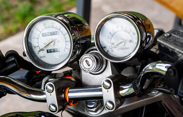 Pointer chrome speedometer and tachometer with a keyhole on the handlebars of a motorcycle close-up...