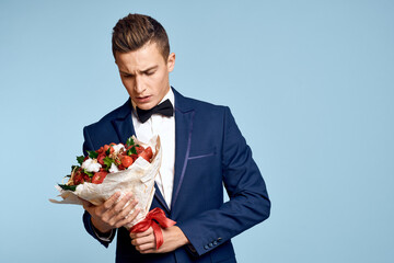 romantic man with a bouquet of flowers and in a bow tie on a blue background cropped view