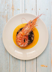 Black rice with shrimps and cremy pumpkin soup in a white plate