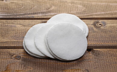 Absorbent cotton wool pads, swabs, round wadding on wooden plank table background and texture