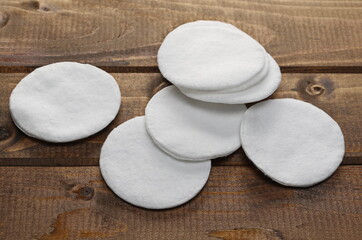 Absorbent cotton wool pads, swabs, round wadding on wooden plank table background and texture