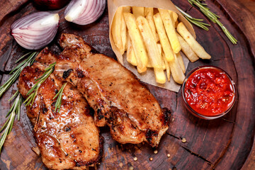 Fried meat with spices and vegetables on a wooden board. European cuisine.