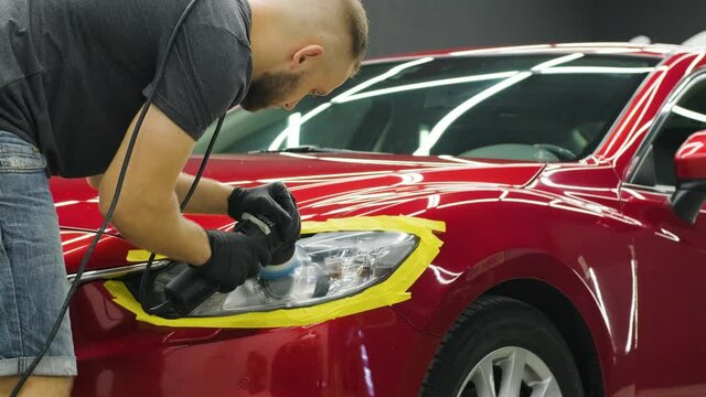 Headlight Polishing, processing of car lights. A car service worker polishes the headlight of a passenger car. Professional polishing.