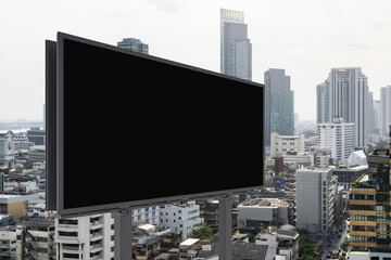 Blank black road billboard with Bangkok cityscape background at day time. Street advertising poster, mock up, 3D rendering. Side view. The concept of marketing communication to promote or sell idea.