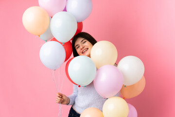 Fototapeta na wymiar Young Ukrainian teenager girl holding lots of balloons over isolated pink background