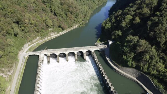 Aerial view of an historic hydroelectric power plant located on a river bank, which exploits the difference in height created by the dam on the Adda river, Italy